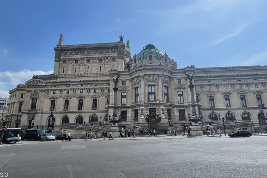 The opulent exterior of Palais Garnier, showcasing its ornate sculptures, golden accents, and majestic columns