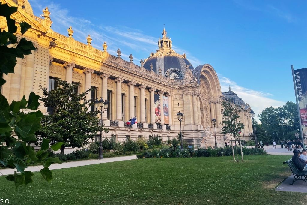 The elegant Petit Palais, showcasing its Beaux-Arts architecture with ornate columns and a beautifully landscaped garden.