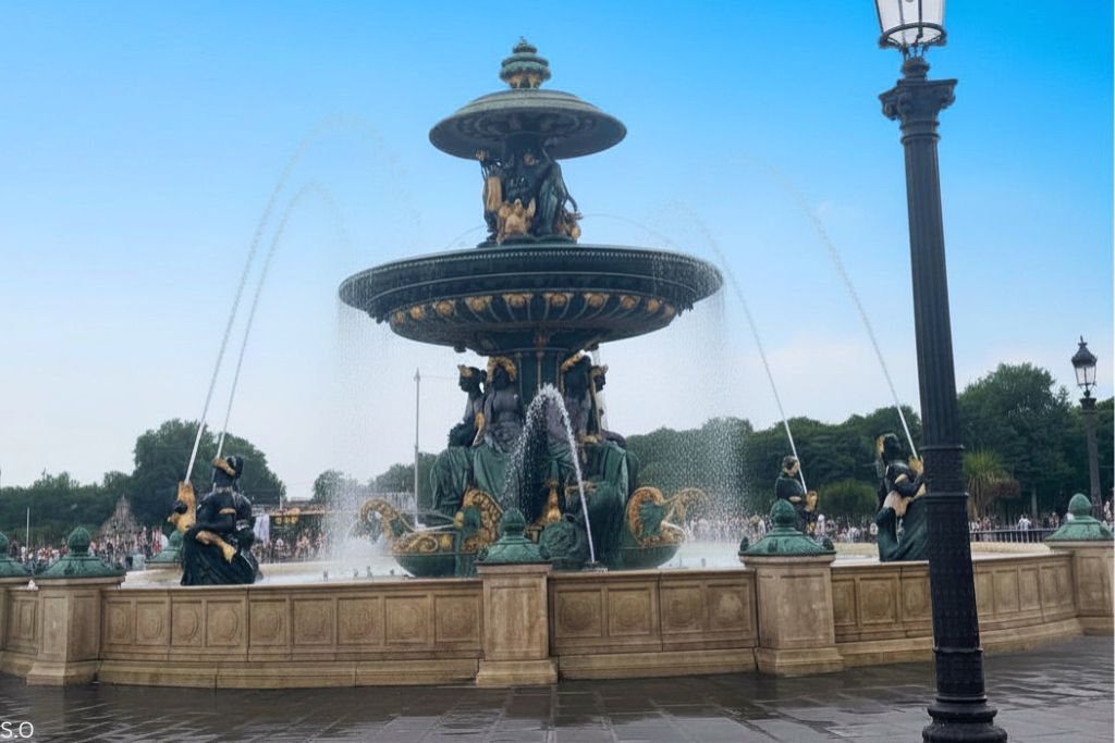 The ornate fountain at Place de la Concorde, adorned with intricate sculptures and cascading water, set against the backdrop of Parisian elegance.
