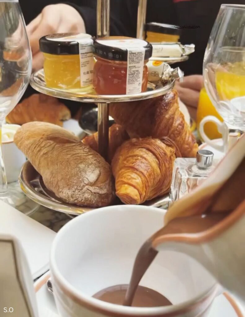 Hot chocolate and a croissant served for breakfast at Angelina café in an elegant Paris dining room.