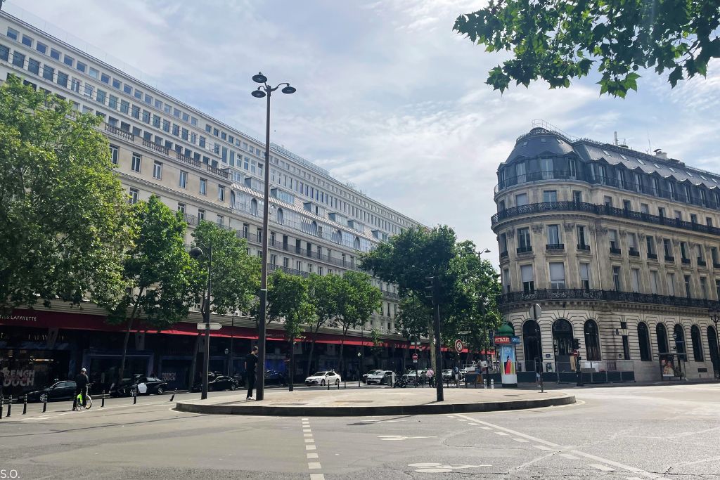 Boulevard Haussmann in Paris with grand façades, broad sidewalks, and elegant storefronts.